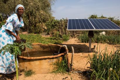 Woman gathering water near solar panel